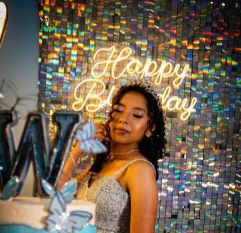 Debutante ao lado do bolo com painel Happy Birthday
