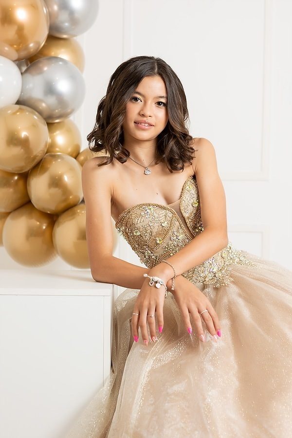 Debutante de vestido dourado com balões dourados em estúdio