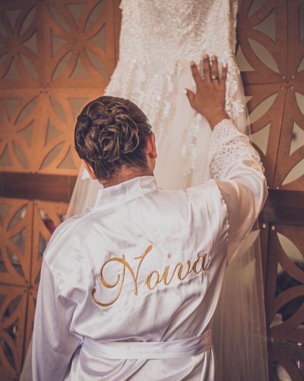 Noiva de robe bordado admirando o vestido pendurado